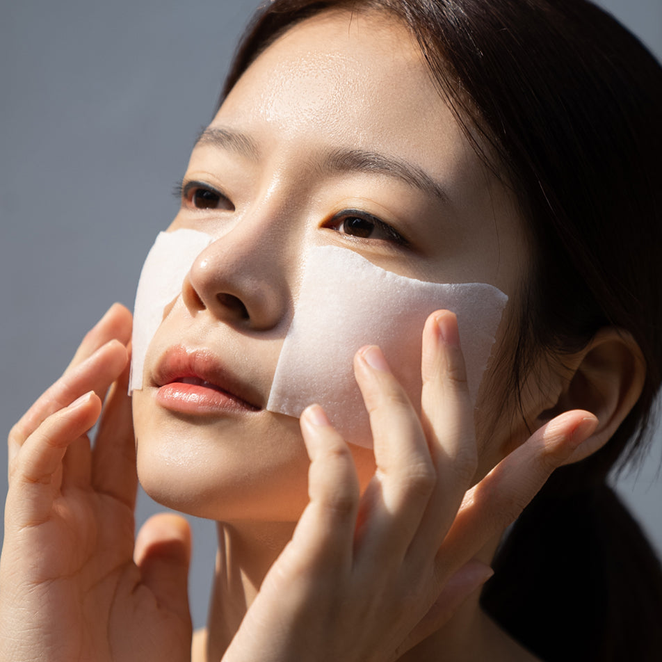 Woman with cotton pads on her face to absorb moisturizer